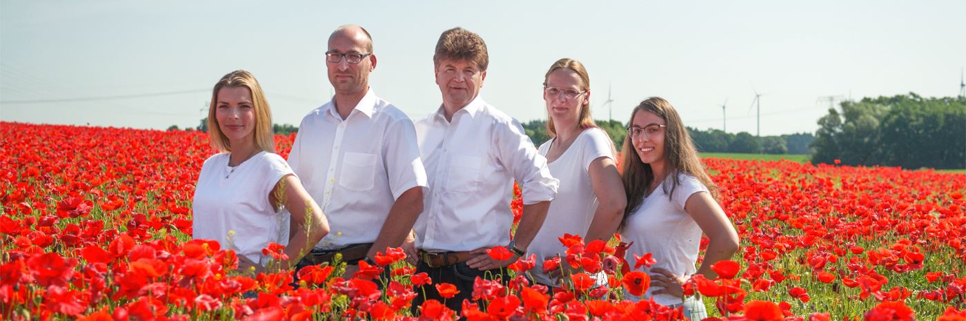 Teamfoto im Mohnfeld, Mitarbeiter tragen weiße Kleidung